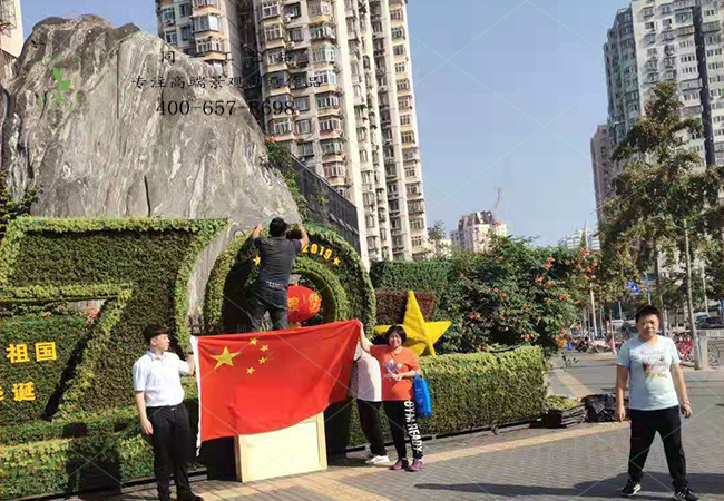 北京游客在植物綠雕國(guó)慶綠雕前舉國(guó)旗合影